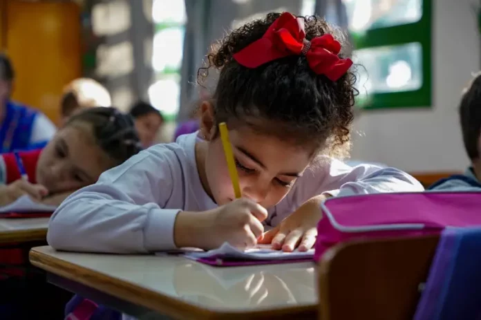 Menina participando de atividades em sala de aula da educação infantil, representando o período em que os estudantes poderão realizar matrículas e transferências escolares.