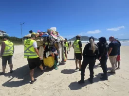 Agentes da Prefeitura e da Polícia Militar abordam um carrinho carregado de produtos irregulares nas praias para ilustrar a fiscalização contra o comércio ambulante ilegal em Florianópolis.