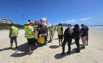 Agentes da Prefeitura e da Polícia Militar abordam um carrinho carregado de produtos irregulares nas praias para ilustrar a fiscalização contra o comércio ambulante ilegal em Florianópolis.