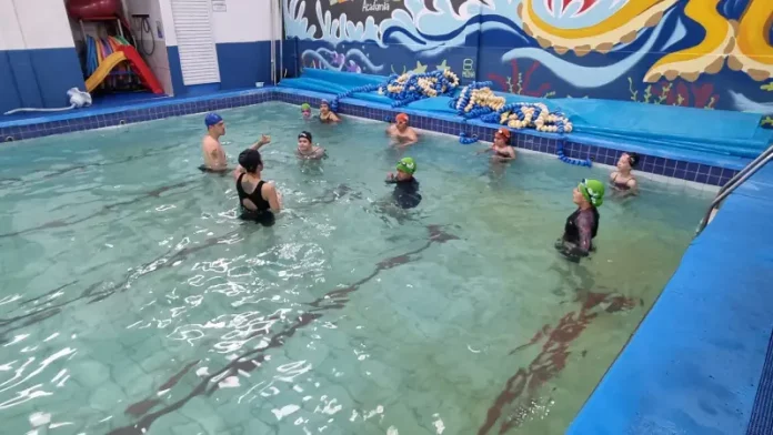 aulas natação SJ Crianças participando de aulas de natação com instrutores, ilustrando o projeto voltado à prevenção de afogamentos em São José.