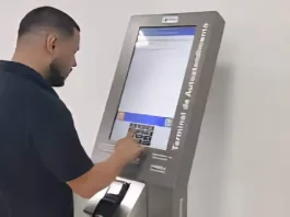 Homem utiliza um terminal de autoatendimento da Celesc para emitir segunda via ou regularizar serviços, mostrando a finalidade de facilitar o acesso rápido aos procedimentos da companhia.