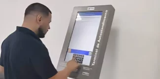 Homem utiliza um terminal de autoatendimento da Celesc para emitir segunda via ou regularizar serviços, mostrando a finalidade de facilitar o acesso rápido aos procedimentos da companhia.