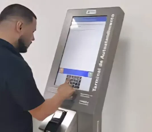 Homem utiliza um terminal de autoatendimento da Celesc para emitir segunda via ou regularizar serviços, mostrando a finalidade de facilitar o acesso rápido aos procedimentos da companhia.
