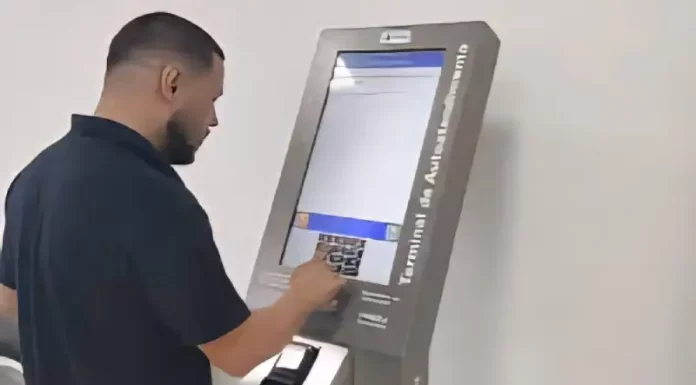 Homem utiliza um terminal de autoatendimento da Celesc para emitir segunda via ou regularizar serviços, mostrando a finalidade de facilitar o acesso rápido aos procedimentos da companhia.