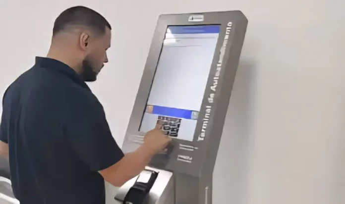 Homem utiliza um terminal de autoatendimento da Celesc para emitir segunda via ou regularizar serviços, mostrando a finalidade de facilitar o acesso rápido aos procedimentos da companhia.