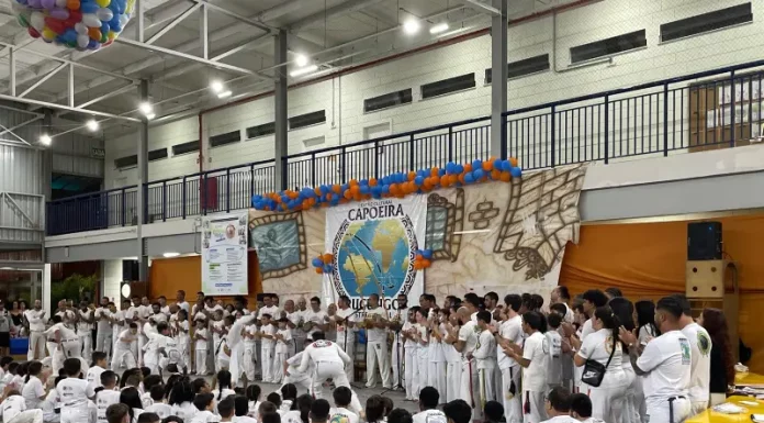 Alunos do Educandário Santa Catarina com trajes de capoeira participam da cerimônia de troca de faixa no ginásio, durante o Encontro Nacional de Capoeira.