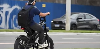 Menino pedala uma bicicleta elétrica em área urbana para ilustrar as novas regras de circulação que passam a exigir CNH, placa e capacete para ciclomotores.