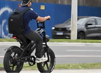 Menino pedala uma bicicleta elétrica em área urbana para ilustrar as novas regras de circulação que passam a exigir CNH, placa e capacete para ciclomotores.