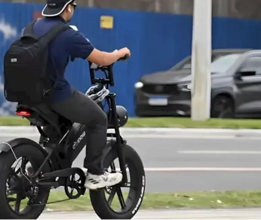 Nova regra vai exigir CNH, placa e capacete para todos os ciclomotores Menino pedala uma bicicleta elétrica em área urbana para ilustrar as novas regras de circulação que passam a exigir CNH, placa e capacete para ciclomotores.