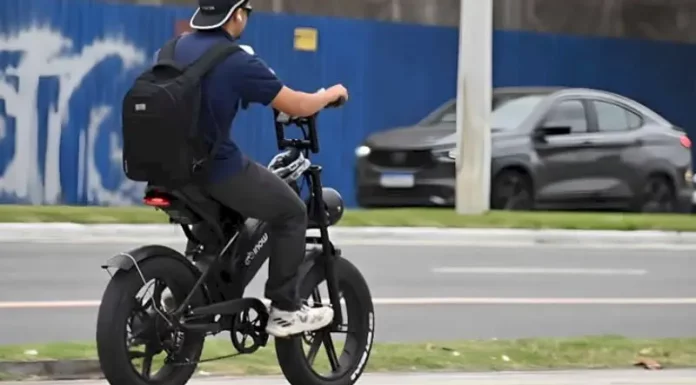 Nova regra vai exigir CNH, placa e capacete para todos os ciclomotores Menino pedala uma bicicleta elétrica em área urbana para ilustrar as novas regras de circulação que passam a exigir CNH, placa e capacete para ciclomotores.