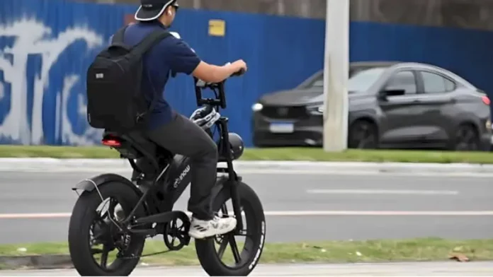 Menino pedala uma bicicleta elétrica em área urbana para ilustrar as novas regras de circulação que passam a exigir CNH, placa e capacete para ciclomotores.