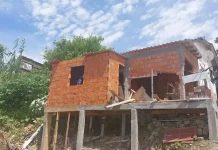 Operários demolindo uma construção irregular em um costão à beira-mar.