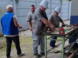 São José oferta 99 vagas de emprego e amplia cursos gratuitos de qualificação profissional Imagem de operários em uma serralheria, usando uniformes e equipamentos de proteção individual, ilustrando as vagas de emprego disponíveis em São José.