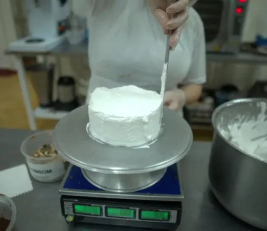 Trabalho e qualificação mudam a rotina de mulheres em unidades prisionais de Santa Catarina Pessoa realiza trabalho de confeitaria ao aplicar cobertura em um bolo na cozinha de uma unidade prisional, durante atividade de capacitação profissional.