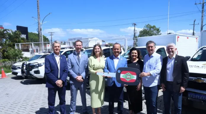 Foto mostra o governador de Santa Catarina, ao lado de autoridades, entregando a chave simbólica das novas viaturas à Polícia Científica durante o lançamento do Programa Identidade Catarina, simbolizando o investimento na modernização da segurança pública.