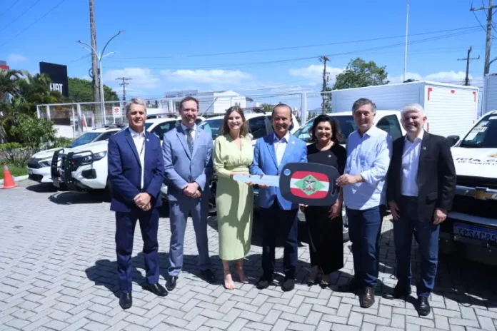 Foto mostra o governador de Santa Catarina, ao lado de autoridades, entregando a chave simbólica das novas viaturas à Polícia Científica durante o lançamento do Programa Identidade Catarina, simbolizando o investimento na modernização da segurança pública.