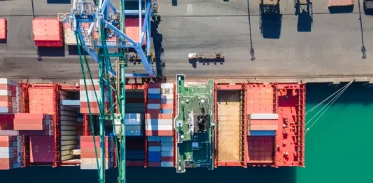 Vista aérea de terminal portuário com contêineres e navios, simbolizando o crescimento das exportações de Santa Catarina.