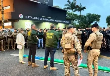 A imagem mostra o efetivo reunido em frente ao Batalhão de Operações Policiais Especiais antes do início da Operação Free Way. A cena registra o alinhamento das equipes do GAECO, Ministério Público e Polícia Militar, evidenciando a preparação conjunta para o cumprimento dos mandados e para a atuação coordenada no combate ao tráfico de drogas na Grande Florianópolis.