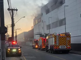 Viaturas do Corpo de Bombeiros atuam em frente ao Shopping ViaCatarina, em Palhoça, durante o combate a um incêndio que gerou intensa fumaça no prédio. A imagem mostra a operação de emergência na madrugada.