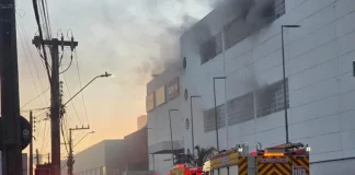 Viaturas do Corpo de Bombeiros atuam em frente ao Shopping ViaCatarina, em Palhoça, durante o combate a um incêndio que gerou intensa fumaça no prédio. A imagem mostra a operação de emergência na madrugada.