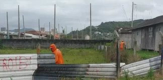 Funcionários da Prefeitura de São José desmontam cerca em terreno público para impedir ocupação irregular e proteger a área municipal.
