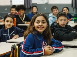 Alunos do Ensino Fundamental participando de atividades em sala de aula, com foco no aprendizado e interação entre estudantes e professor.