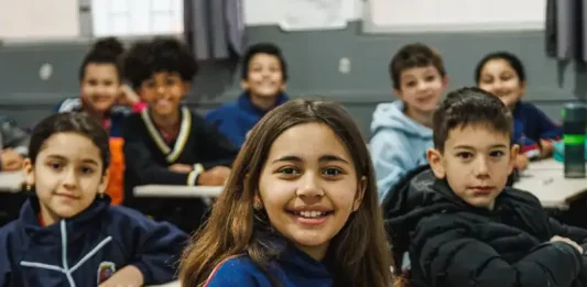 Alunos do Ensino Fundamental participando de atividades em sala de aula, com foco no aprendizado e interação entre estudantes e professor.