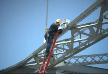 Trabalhador instala uma câmera de monitoramento na estrutura da Ponte Hercílio Luz para reforçar a segurança com tecnologia de vigilância.