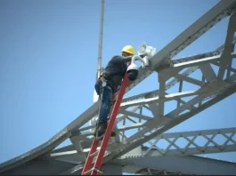 Trabalhador instala uma câmera de monitoramento na estrutura da Ponte Hercílio Luz para reforçar a segurança com tecnologia de vigilância.