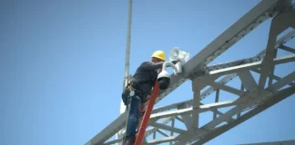 Trabalhador instala uma câmera de monitoramento na estrutura da Ponte Hercílio Luz para reforçar a segurança com tecnologia de vigilância.