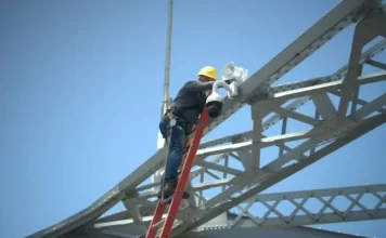Trabalhador instala uma câmera de monitoramento na estrutura da Ponte Hercílio Luz para reforçar a segurança com tecnologia de vigilância.