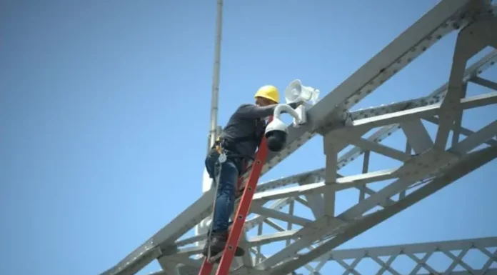 Trabalhador instala uma câmera de monitoramento na estrutura da Ponte Hercílio Luz para reforçar a segurança com tecnologia de vigilância.