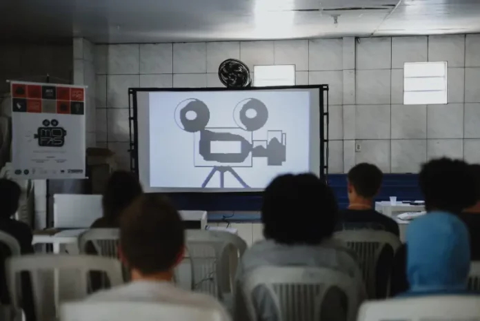 Estudantes assistindo a uma sessão de cinema da Mostra Mofas na Tapera, ilustrando as exibições gratuitas realizadas nas escolas do bairro.