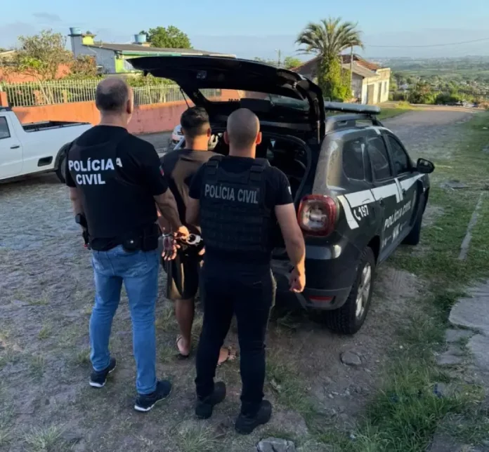 Policiais conduzem um homem preso até a viatura durante operação de combate a fraudes em sistemas digitais.