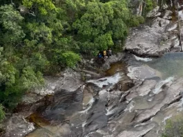 Bombeiros resgatam adolescente após queda na Cachoeira do Jarrão, em Palhoça Imagem mostra bombeiros realizando o resgate de uma adolescente ferida em área de cachoeira, ilustrando a operação em terreno íngreme e de difícil acesso.