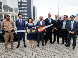 Governador e vice-governadora posam com uma chave simbólica que representa a entrega de novas viaturas para reforçar a estrutura da Polícia Civil.