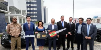 Governador e vice-governadora posam com uma chave simbólica que representa a entrega de novas viaturas para reforçar a estrutura da Polícia Civil.
