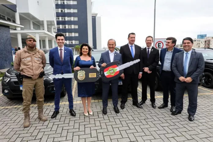 Governador e vice-governadora posam com uma chave simbólica que representa a entrega de novas viaturas para reforçar a estrutura da Polícia Civil.