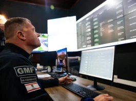 Agente da Guarda Municipal de Florianópolis monitora imagens da cidade em tempo real na central de videomonitoramento, demonstrando o uso de câmeras com tecnologia de reconhecimento facial para reforçar a segurança pública.