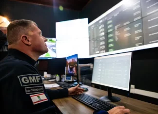 Agente da Guarda Municipal de Florianópolis monitora imagens da cidade em tempo real na central de videomonitoramento, demonstrando o uso de câmeras com tecnologia de reconhecimento facial para reforçar a segurança pública.