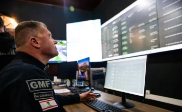 Agente da Guarda Municipal de Florianópolis monitora imagens da cidade em tempo real na central de videomonitoramento, demonstrando o uso de câmeras com tecnologia de reconhecimento facial para reforçar a segurança pública.