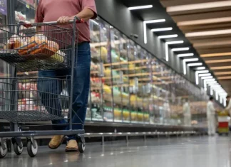 Mulher realizando compras em supermercado, com carrinho contendo alguns produtos, simbolizando o crescimento dos supermercados em 2026