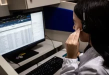 Alô Saúde Floripa oferece atendimento bilíngue 24 horas para turistas Atendente do Alô Saúde Floripa atende ligação de turista enquanto registra informações no computador, mostrando o serviço de suporte médico bilíngue da temporada.