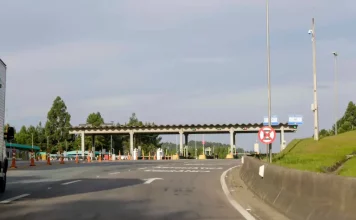 Autopista Planalto Sul terá nova tarifa de pedágio a partir de sexta (19) Imagem mostra uma praça de pedágio da Autopista Planalto Sul na BR-116, com cabines de cobrança, sinalização viária e pistas de acesso, ilustrando o local onde os motoristas realizam o pagamento da tarifa.