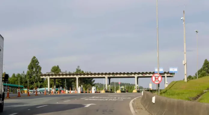 Imagem mostra uma praça de pedágio da Autopista Planalto Sul na BR-116, com cabines de cobrança, sinalização viária e pistas de acesso, ilustrando o local onde os motoristas realizam o pagamento da tarifa.