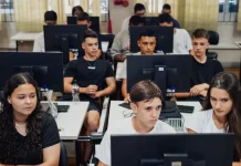 "Estudantes do ensino médio participam de aula prática em laboratório de informática, utilizando computadores lado a lado, representando a formação técnica oferecida pelo programa CaTec+ para preparar jovens para o mercado de trabalho."
