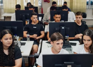 "Estudantes do ensino médio participam de aula prática em laboratório de informática, utilizando computadores lado a lado, representando a formação técnica oferecida pelo programa CaTec+ para preparar jovens para o mercado de trabalho."