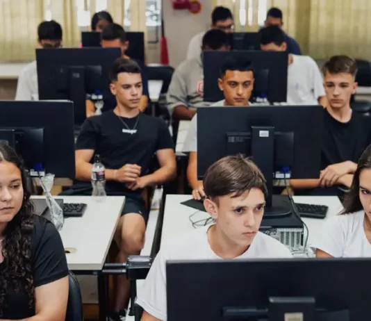"Estudantes do ensino médio participam de aula prática em laboratório de informática, utilizando computadores lado a lado, representando a formação técnica oferecida pelo programa CaTec+ para preparar jovens para o mercado de trabalho."