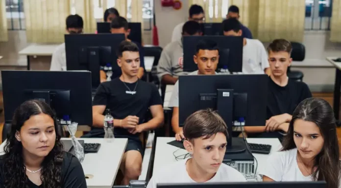 "Estudantes do ensino médio participam de aula prática em laboratório de informática, utilizando computadores lado a lado, representando a formação técnica oferecida pelo programa CaTec+ para preparar jovens para o mercado de trabalho."