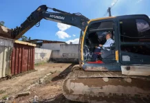 Governador Jorginho Mello ao volante de uma escavadeira durante o ato simbólico de demolição de estruturas do Complexo Penitenciário da Agronômica, em Florianópolis.